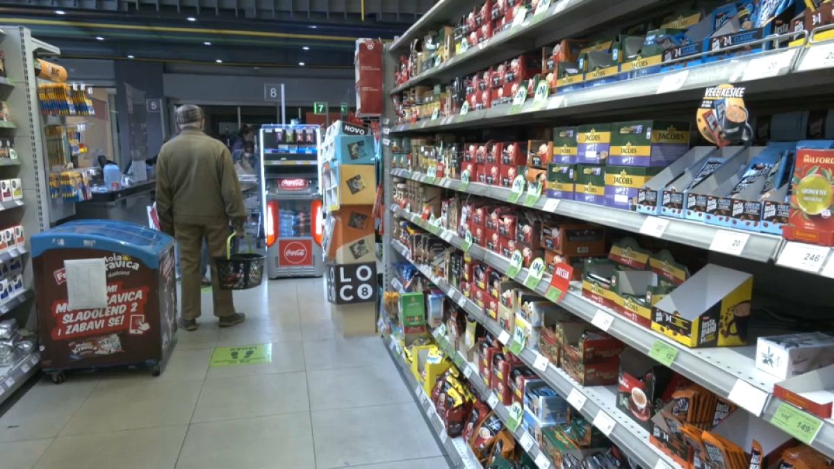 A man is standing in the isle as he is shopping in a grocery store in Serbia. 