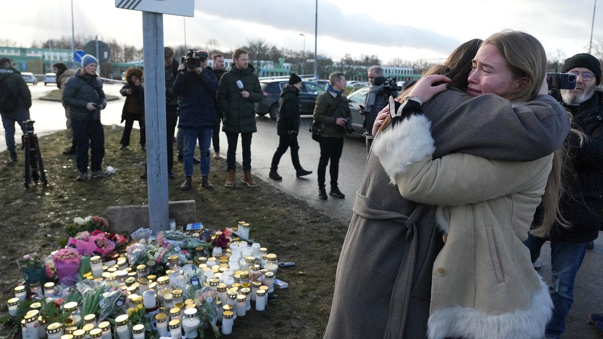 People gather at a makeshift memorial near the scene of a shooting