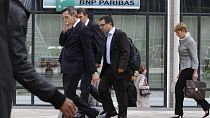 People walk past a logo of the BNP Paribas Bank at Paris business district La Defense, Tuesday, Sept. 20, 2011.