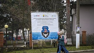 Children walk by a banner presenting a USAID-supported project in Moldova in January 2025.