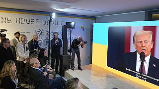 People watch the inauguration speech of Donald Trump on screens at the Ukraine house alongside the World Economic Forum in Davos, Switzerland, Monday, Jan. 20, 2025