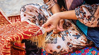 Detail of a female uzbek carpet weaver weaving a typical oriental uzbek silk carpet in Itchan Kala Old Town, Xiva - Khiva - Chiva, Xorazm Region, Uzbekistan, Central Asia
