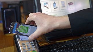 A man uses a mobile device for payment at the Mobile World Congress, the world's largest mobile phone trade show in Barcelona, Spain, Wednesday, Feb. 26, 2014.