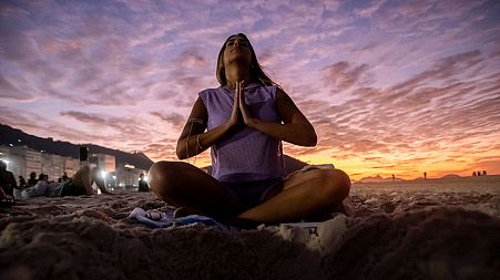 A woman sits in lotus prayer pose during the "Yoga at the Sunrise" event on Copacabana beach, Rio de Janeiro.