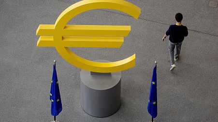 A man walks past a euro sign in the hallway of the European Central Bank in Frankfurt, Germany