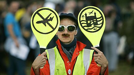 An environmental activist imitates an airport worker near London's Heathrow Airport