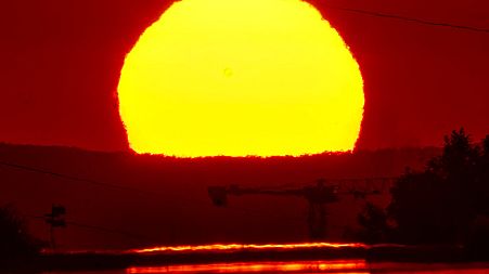 The rising sun is reflected on a small road in the outskirts of Frankfurt, Germany, Saturday, July 2, 2022