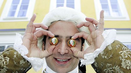 Benjamin Dzialowski, dressed up as Mozart holds Mozart balls against his eyes in front of Mozart's birthplace in the city of Salzburg, on Friday, Jan. 27, 2006