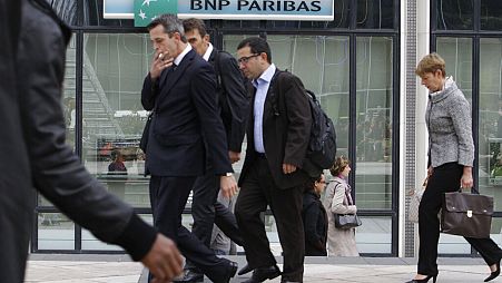 People walk past a logo of the BNP Paribas Bank at Paris business district La Defense, Tuesday, Sept. 20, 2011.