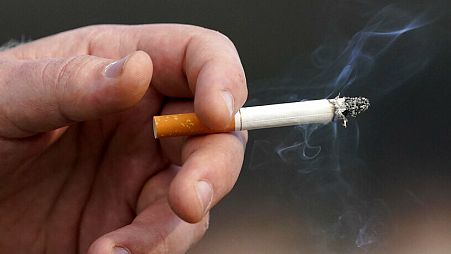 A man holds a lit cigarette while