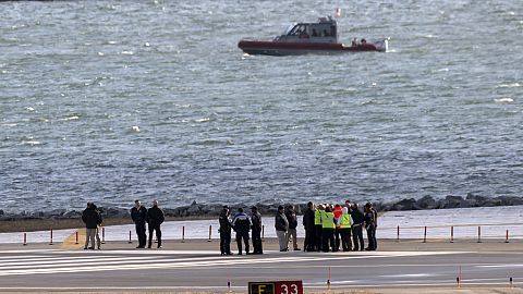 Officials gather at the end of runway 33 near the wreckage site in the Potomac River of a mid-air collision between an American Airlines jet and a Black Hawk helicopter
