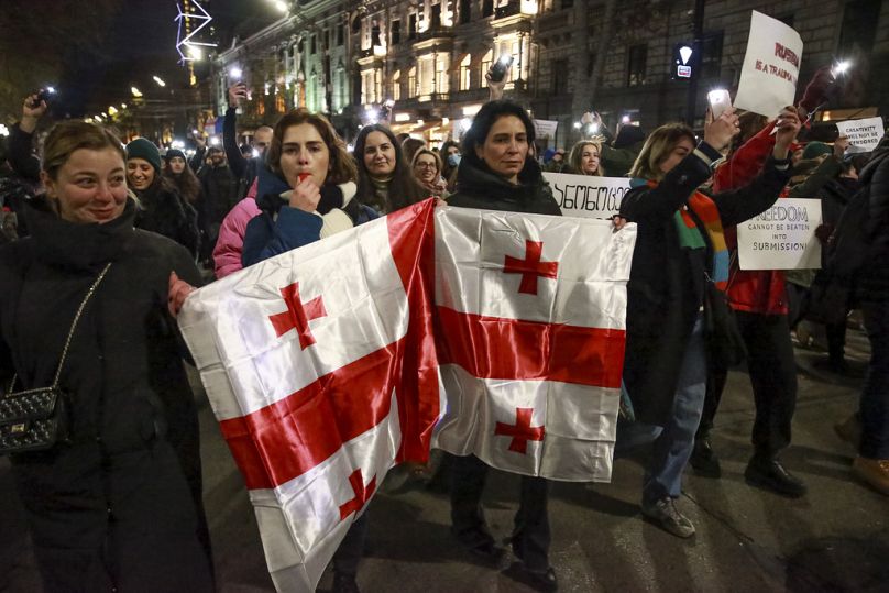 FILE: Demonstrators with a Georgian national flag rally outside the parliament in Tbilisi, Georgia, Tuesday, Dec. 3, 2024