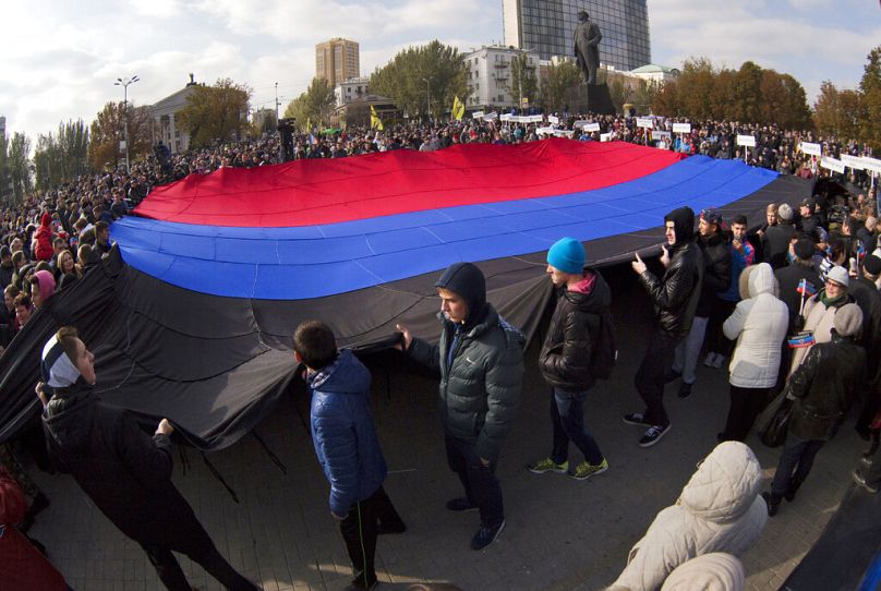 People carry a giant flag during celebration of the Day of the flag of "Donetsk Peoples Republic" in the town of Donetsk, eastern Ukraine Sunday, Oct. 19, 2014.